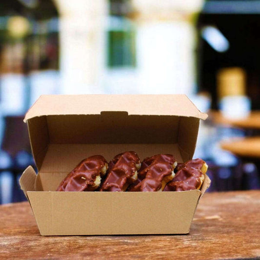 Corrugated clam shell box of chocolate-covered donuts on a wooden table with a blurred background