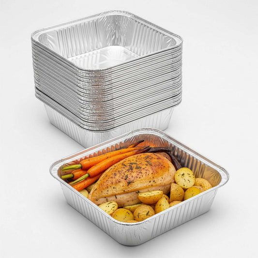 Stack of aluminum food containers with a partially filled one containing roasted vegetables and chicken.