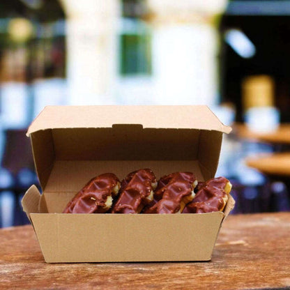 Corrugated clam shell box of chocolate-covered donuts on a wooden table with a blurred background