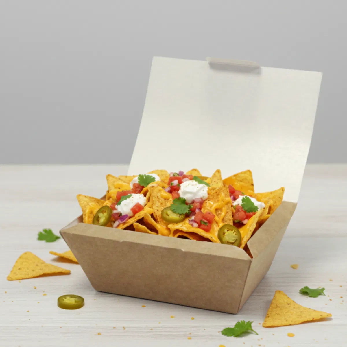 Nacho chips with toppings in a medium kraft nested box on a light surface.