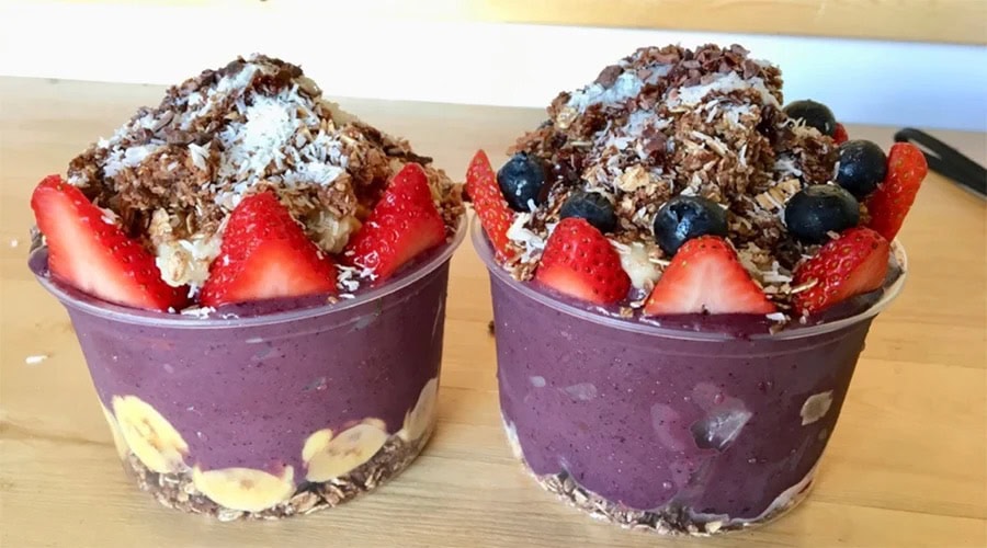 Two bowls 12oz Clear Round RPET Açaí Bowl Container with fruit and toppings on a wooden surface.