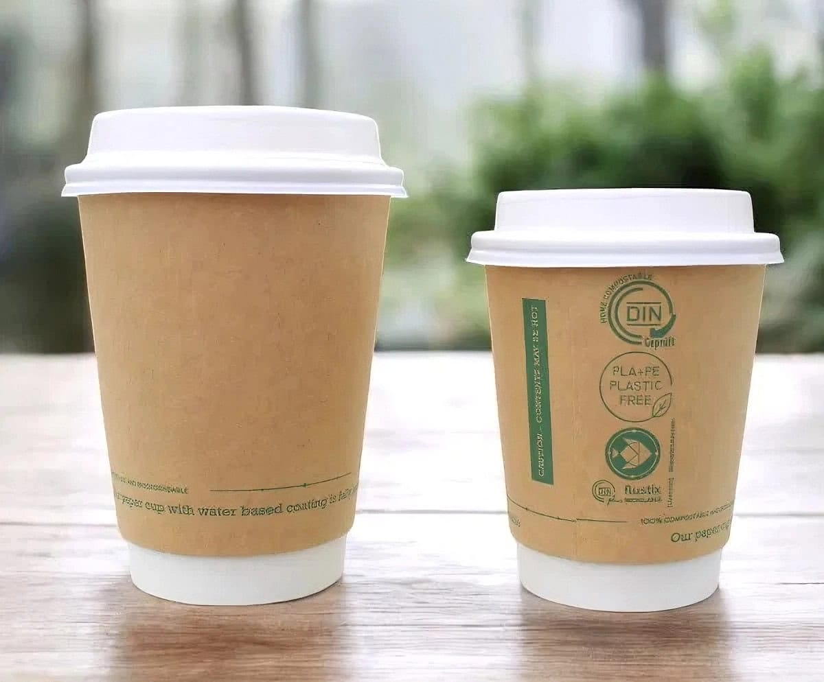 Two 12oz Kraft Aqueous Compostable Hot Cups and Lids on a wooden surface, one with visible branding.