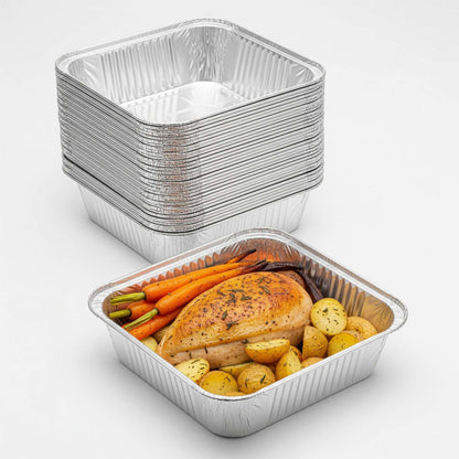 Stack of aluminum food containers with a partially filled one containing roasted vegetables and chicken.