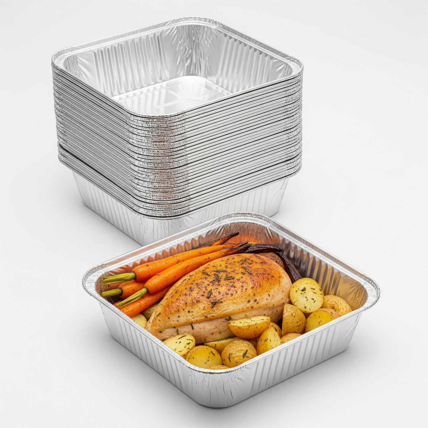 Stack of aluminum food containers with a partially filled one containing roasted vegetables and chicken.