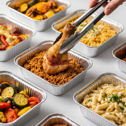 Assorted pre-packaged meals in foil containers on a white surface.