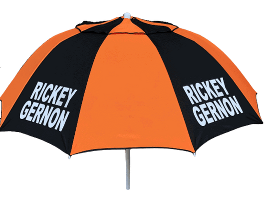 Orange and black racecourse bookmakers umbrella with 'Rickey Gernon branding on a dark background