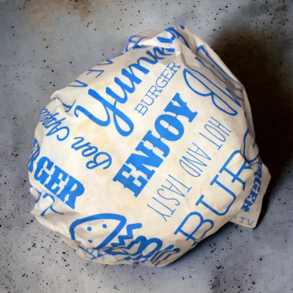 Burger wrapped in paper with blue text on a gray surface