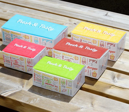 Five colorful Snack boxes with 'Fresh & Tasty' text on a wooden surface