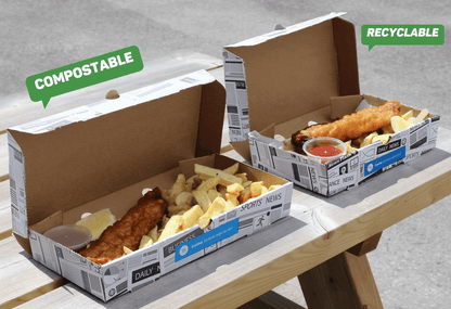 Two cardboard boxes containing food, one labeled 'Compostable' and the other 'Recyclable', on a wooden surface.
