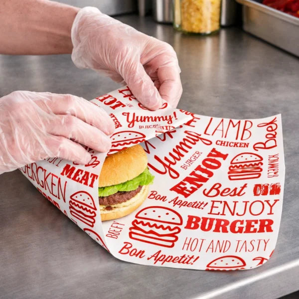 Person holding a Red Burger Wrap with text and graphics on a metallic surface